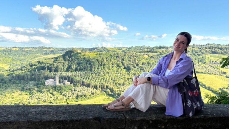 Author Betty sitting on a stone wall at the Anello della Rupe trailhead in Orvieto
