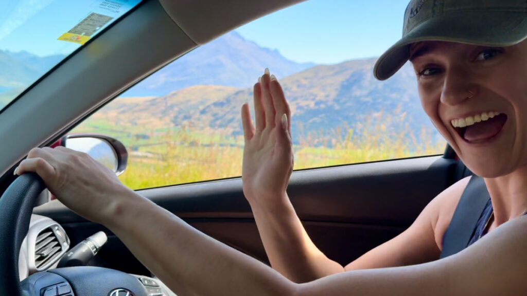 Author Betty waving while driving in Queenstown