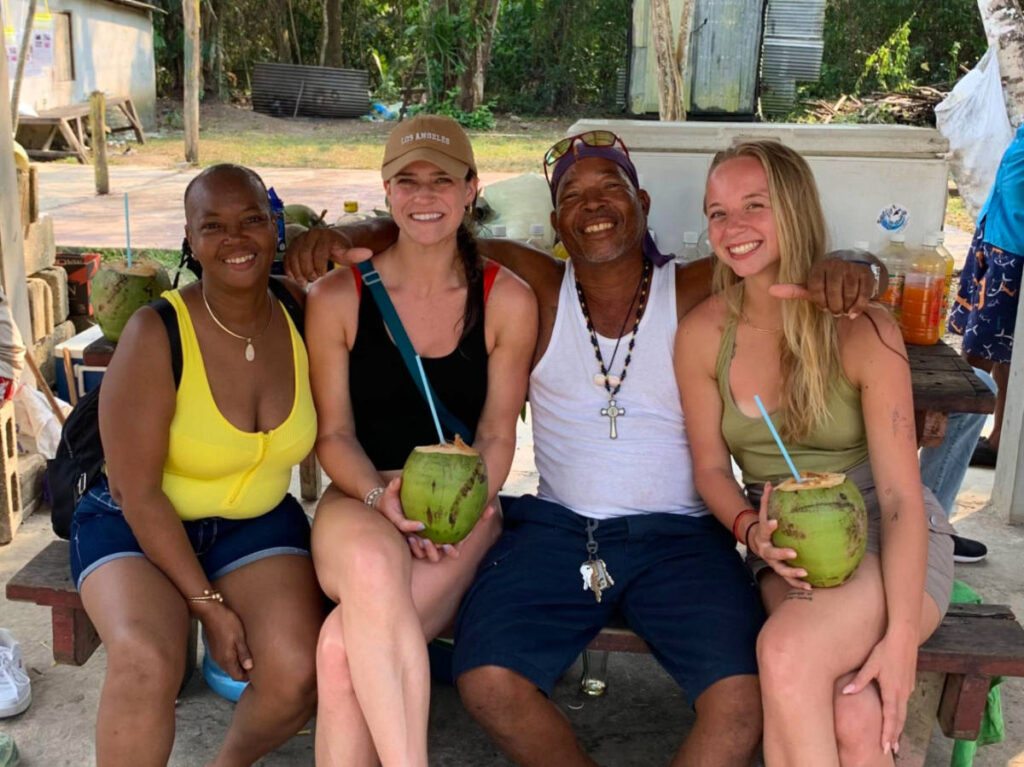 Author Betty with friends drinking coconut juice in Caye Caulker