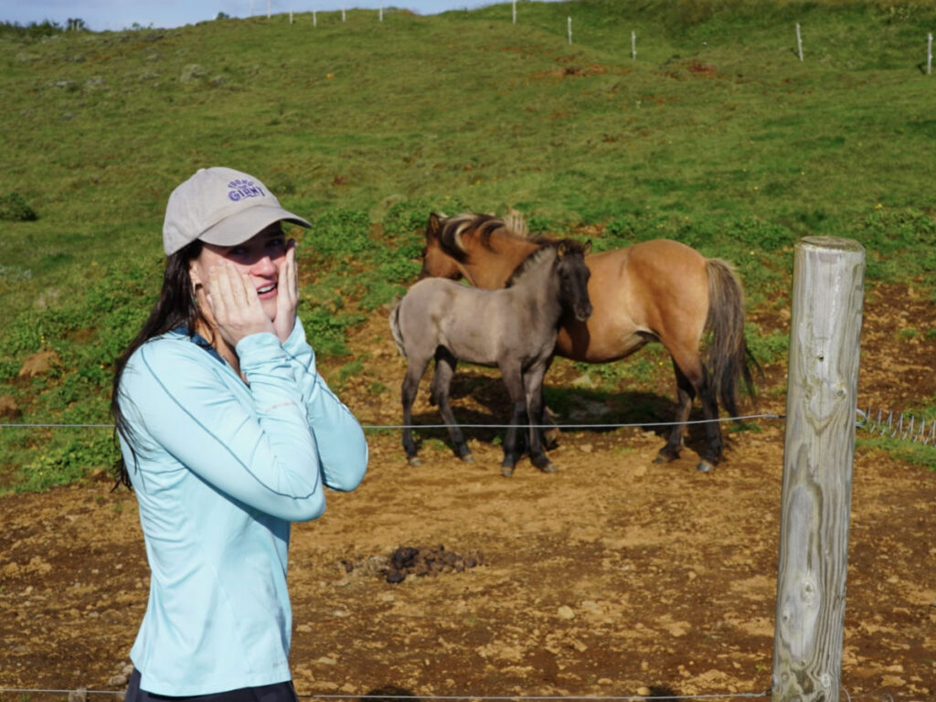 Author Betty standing next to the fence with the horses inside