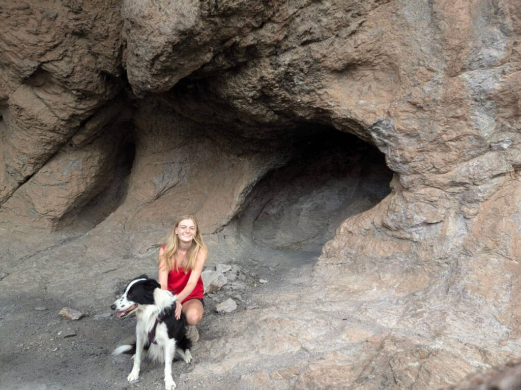 Author Brianna and her dog sitting at a cave in Achenbach Canyon