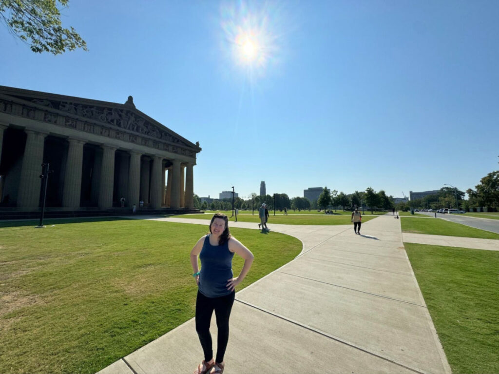 Author Elizabeth in front of the Parthenon in Centennial Park on a sunny day