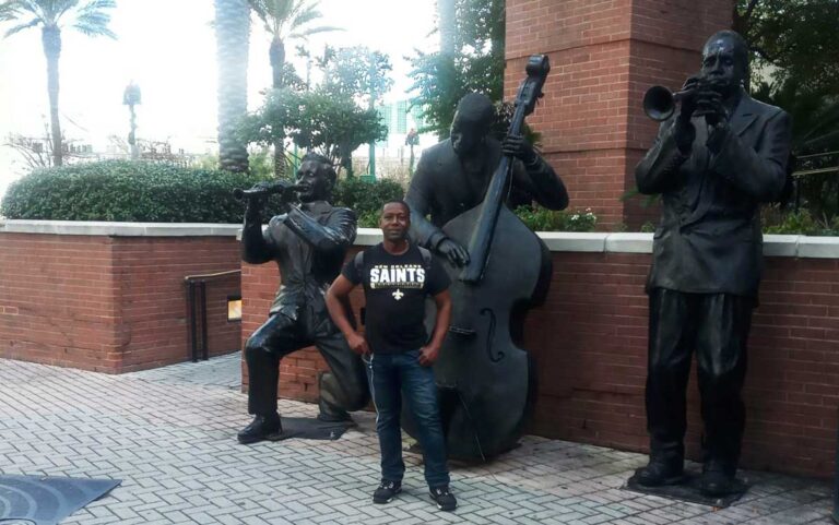 The author Eze posing for a photo in front of the New Orleans Jazz player’s statue