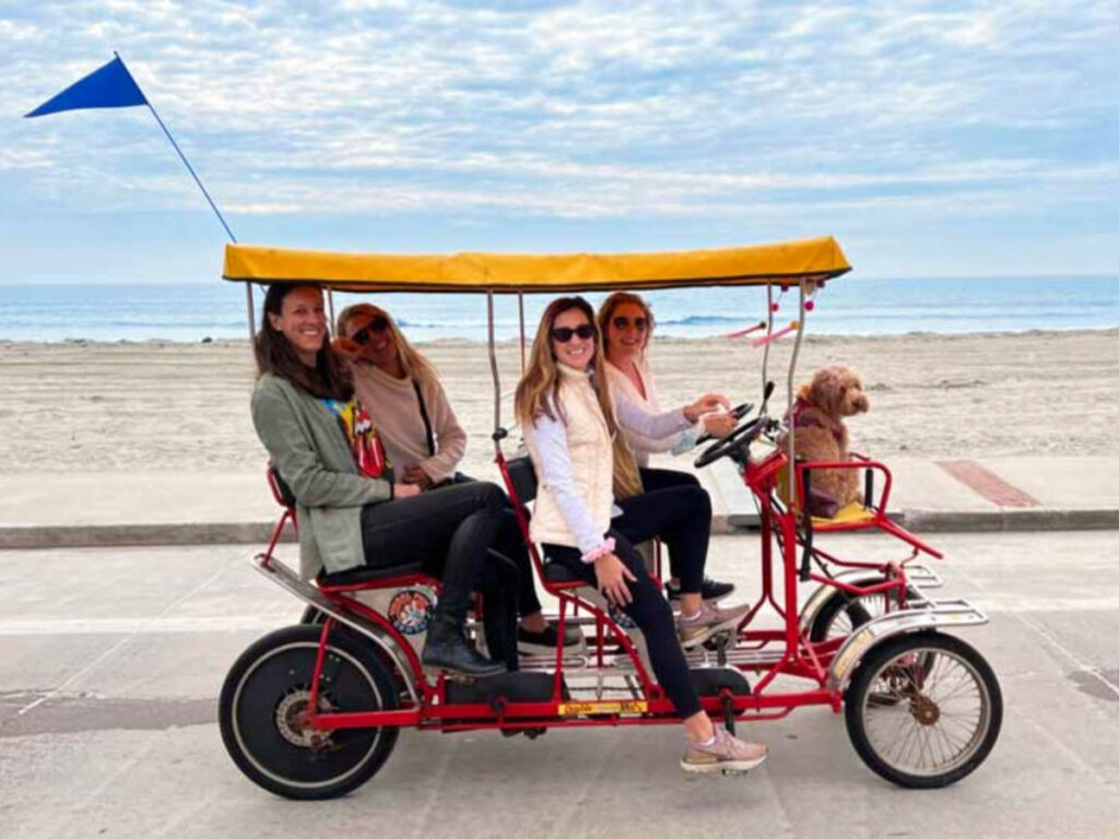 Author Jess and friends with the dog in front riding a 4-wheel cycle down the sandy beach