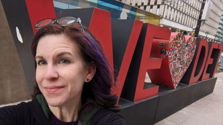 Author Julie taking a selfie at the We Love Detroit sign