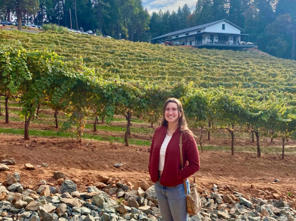 Author Laura standing near the vineyards at Apple Hill