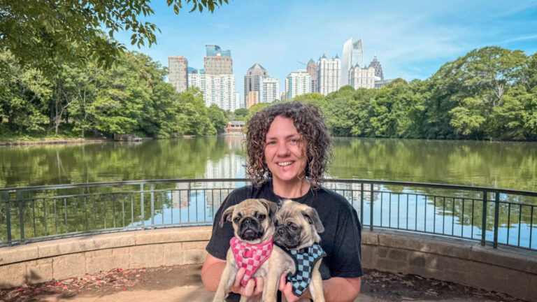 Author Lauren holding her two pugs with the Atlanta skyline in the background