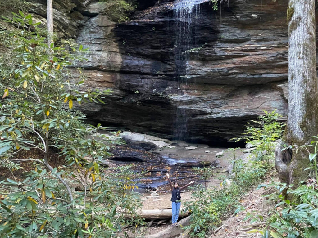 Author Lea Rose standing at the bottom of Moore Cove Falls
