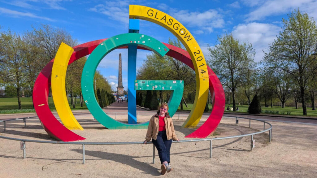 Author Louise sitting in front of the Glasgow 2014 Monument