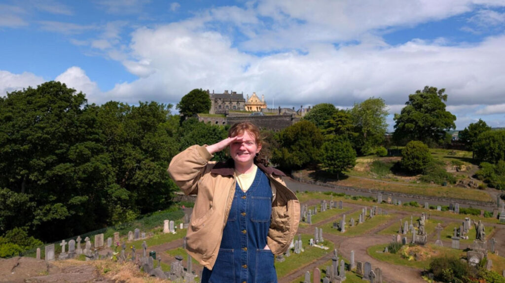 Author Louise standing in front of Stirling Castle and the Old Town Cemetery on a sunny day