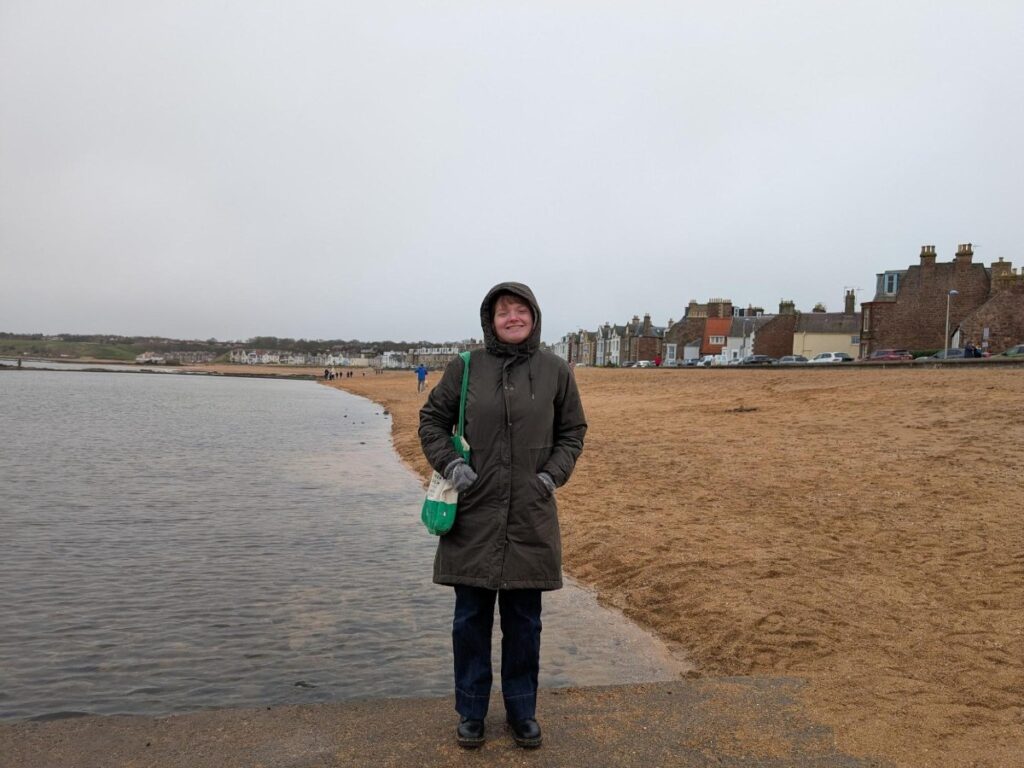 Author Louise standing on North Berwick’s beachfront on a stormy day