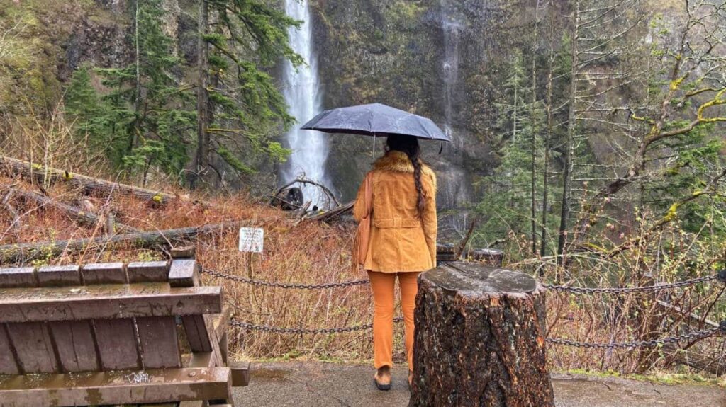 The author McKenna Mobley admiring the Multnomah Falls while holding an umbrella