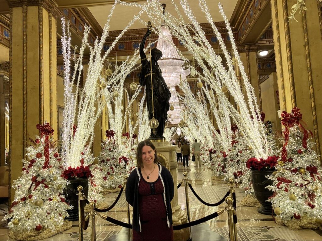 Author Meg posing for a photo in the Roosevelt Hotel lobby during Christmas