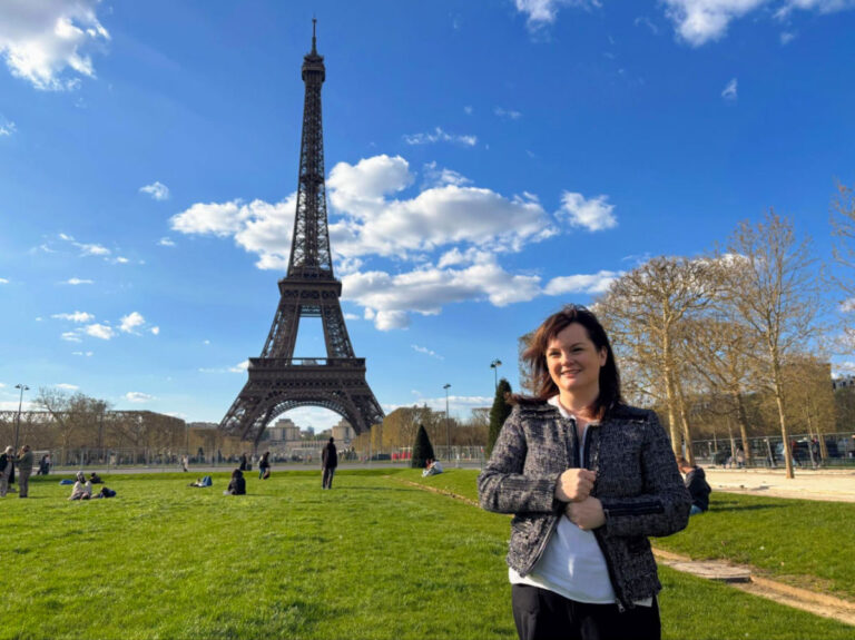 Author Rachel standing in front of the Eiffel Tower on a breezy spring day