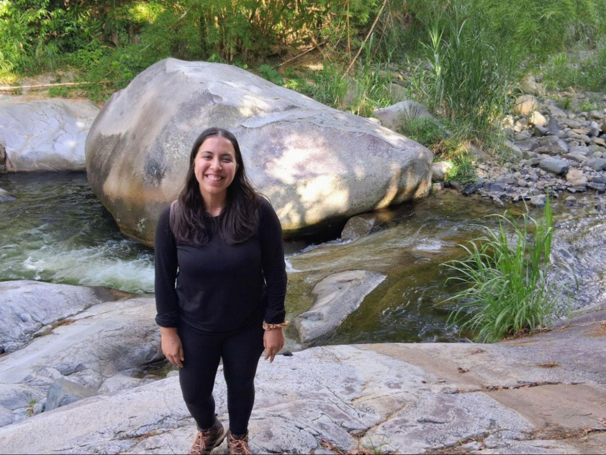 Author Vanessa in La Piedra Escrita with the boulder's petroglyphs seen in the background