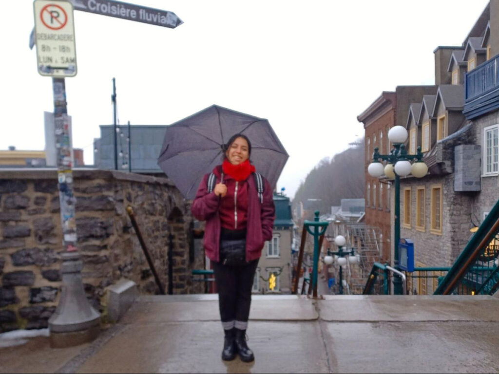 Author Vanessa holding an umbrella and smiling on a rainy day in Old Quebec City