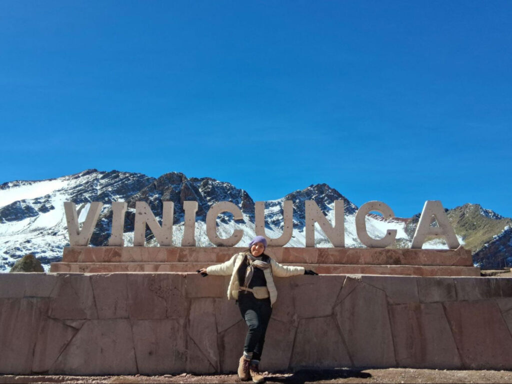 Author Vanessa posing in front of the Vinicunca sign