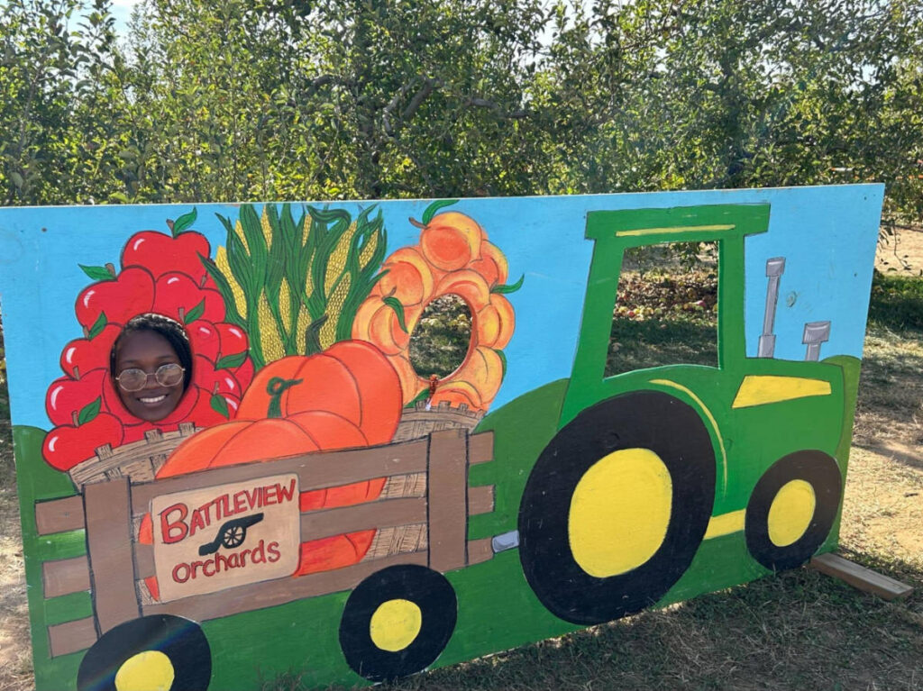 The author's daughter, smiling for a photo behind the cutout photo area at Battleview Orchards