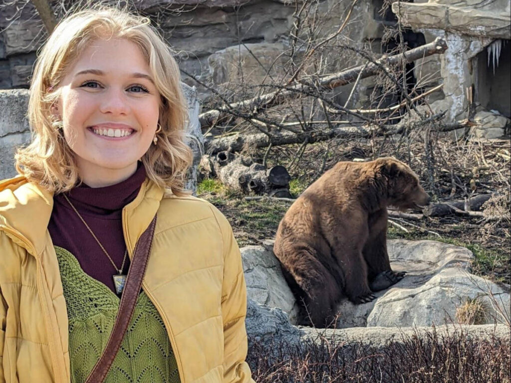 The author's daughter, smiling for a photo with a Grizzly Bear at the Detroit Zoo
