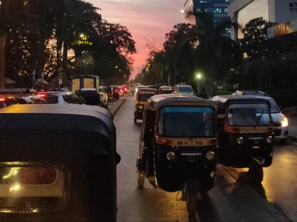 Metered auto-rickshaws and cars stuck in evening traffic on a Mumbai street