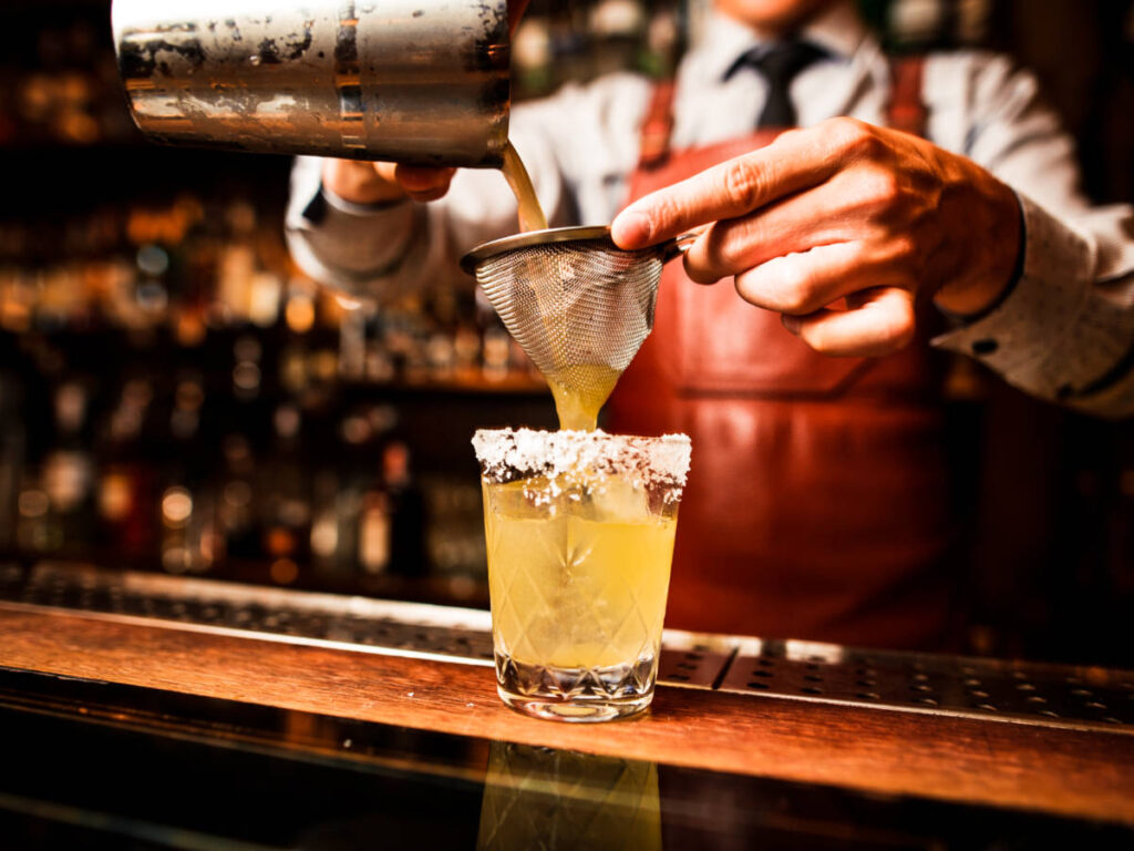 The bartender's hands making a cocktail at the bar counter