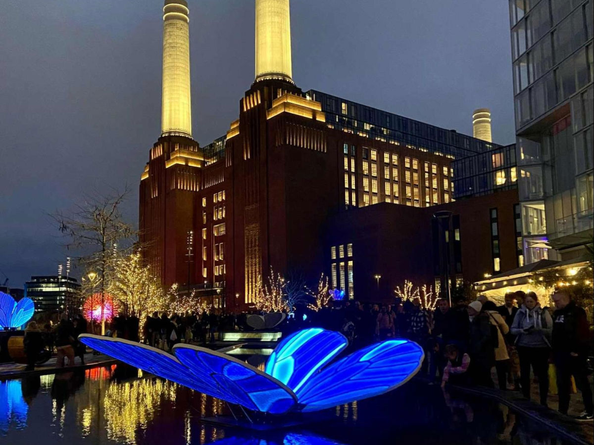 People looking at the butterfly sculptures at Battersea Power Station at night