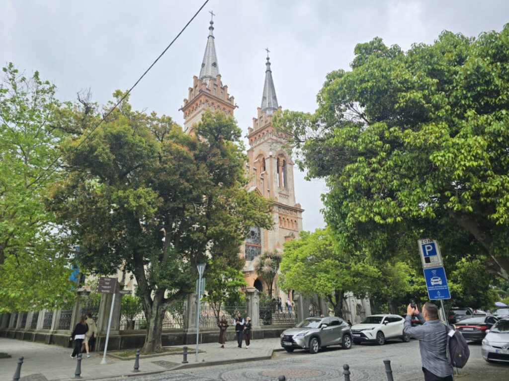View of the Gothic spires of Batumi Cathedral behind the trees