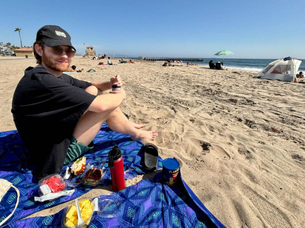 Michael sitting on the picnic blanket at Playa del Rey Beach