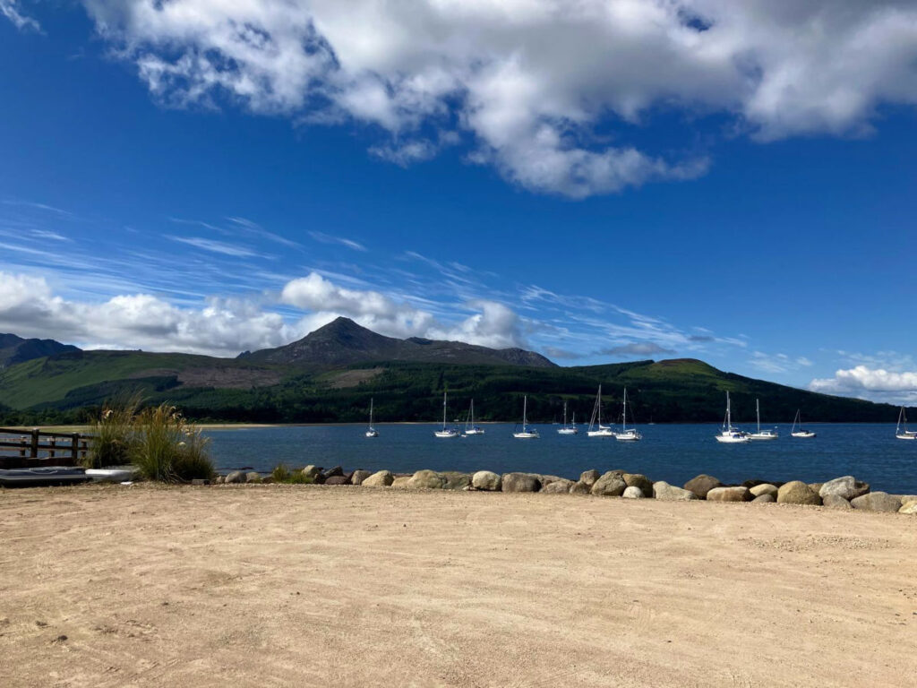 Sailboats float in Brodick Bay against the backdrop of Goat Fell mountain