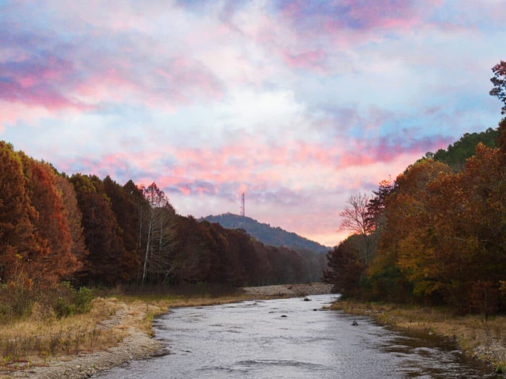 View of the river surrounded by fall foliage in Beavers Bend State Park at sunset