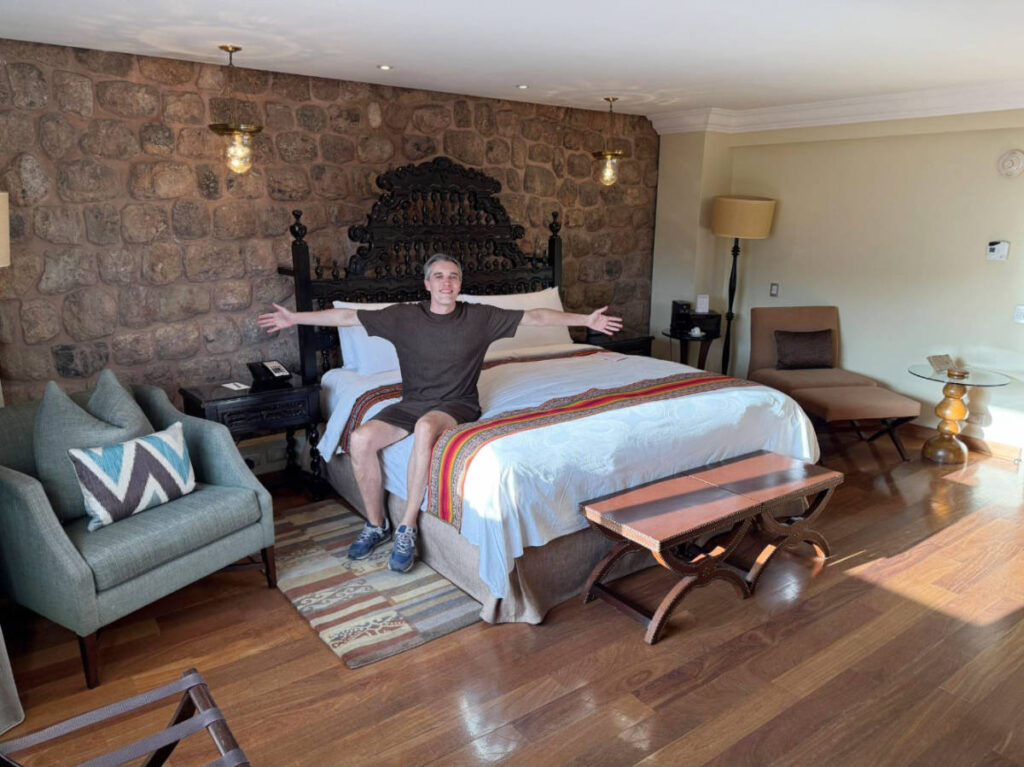 The author, Nate Hake posing for a photo on their bed at JW Marriott El Convento Cusco