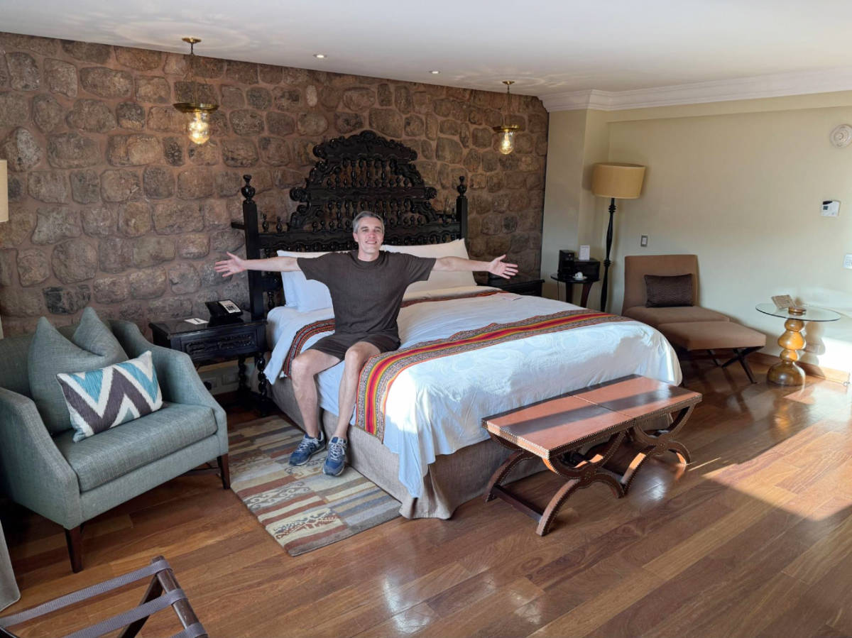 The author, Nate Hake posing for a photo on their bed at JW Marriott El Convento Cusco