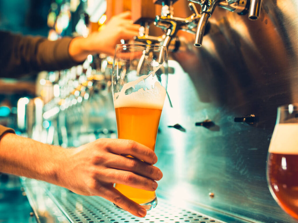 Hand of bartender pouring a large lager beer in tap
