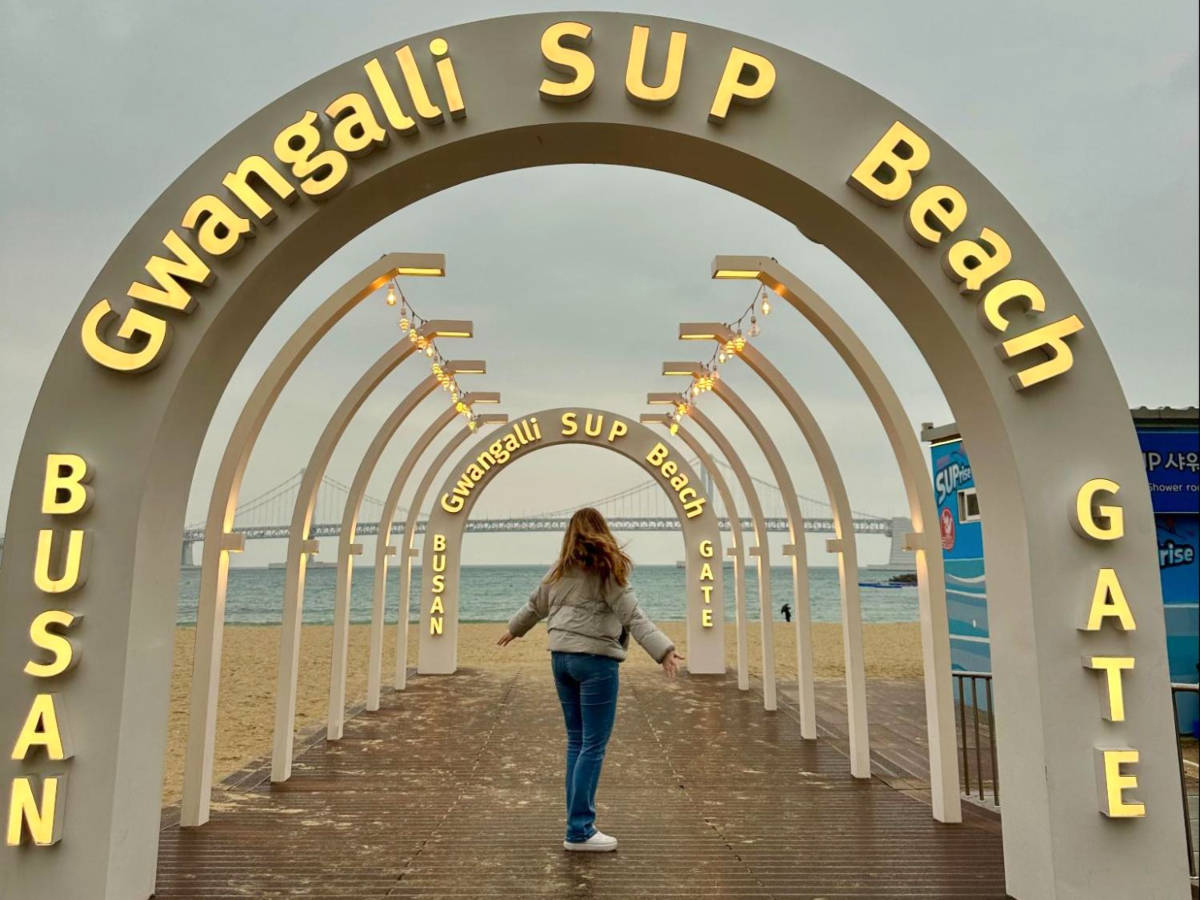 The author Bethan Nutting at the arch sign in Gwangalli Beach with Gwangan Bridge view