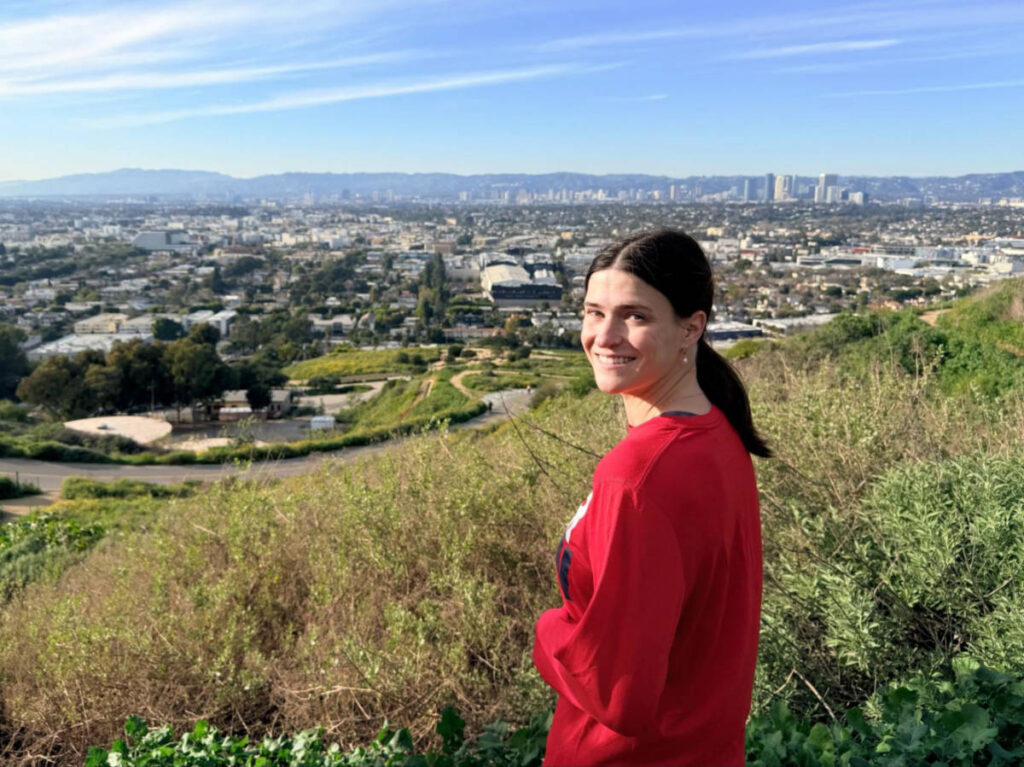 Travel Lemming writer, Betty Hurd, posing for a photo at the Baldwin Hills Scenic Overlook with overlooking views