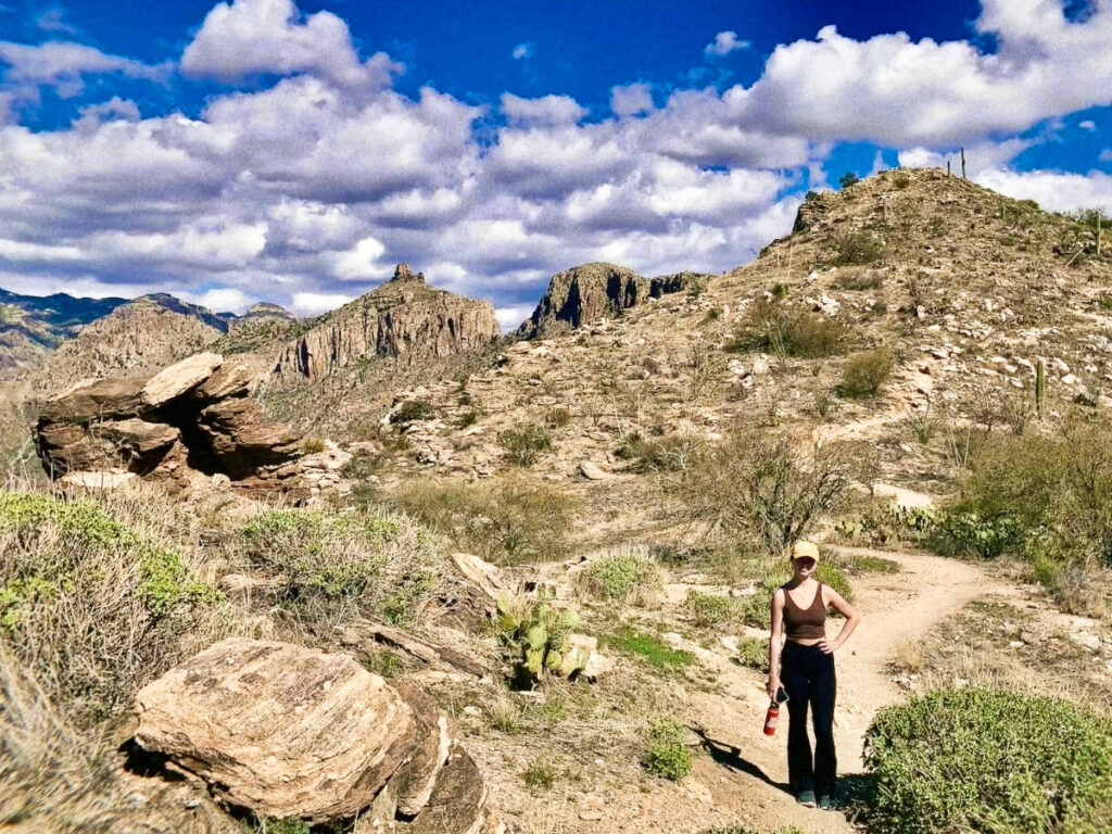 A woman posing for a photo in the trail on a sunny day