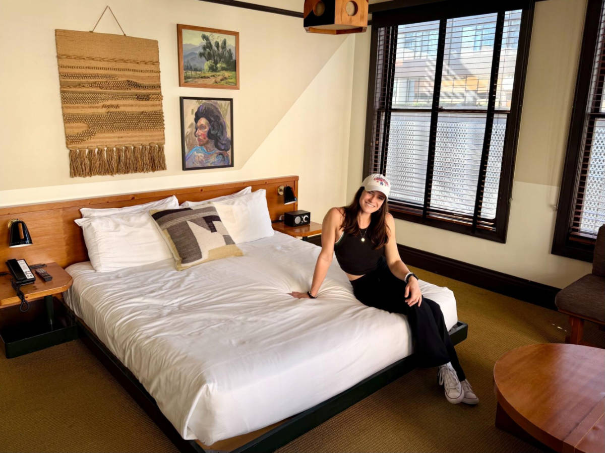 The author Betty Hurd, sitting on the bed in a deluxe king room at the Freehand hotel