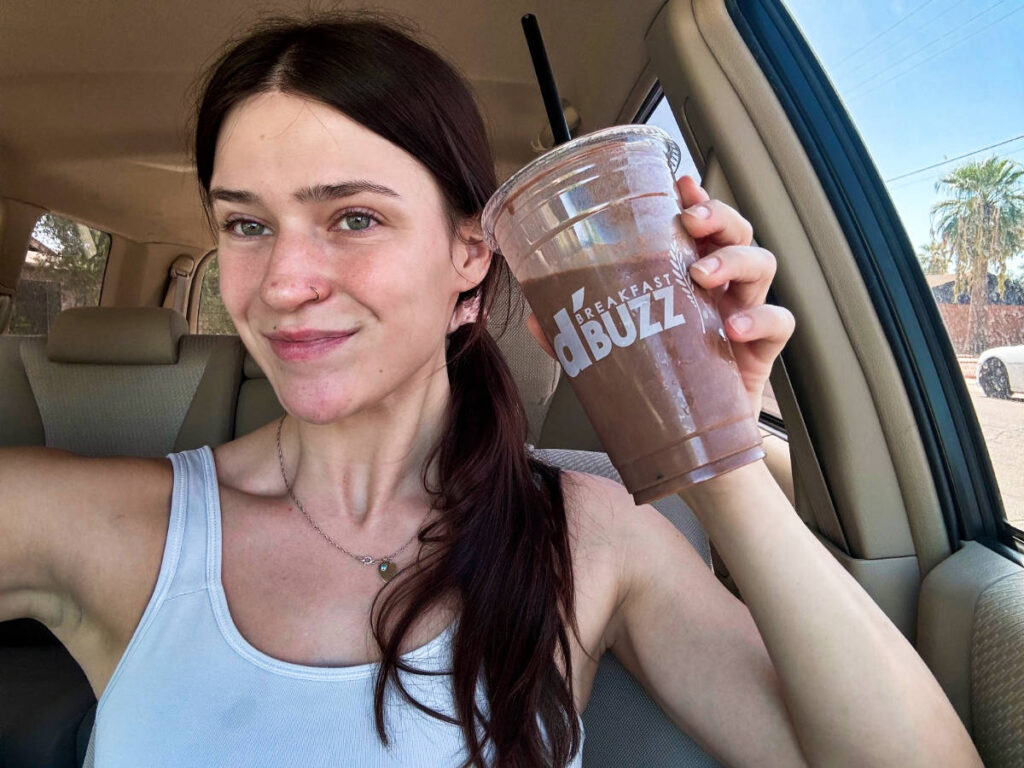 The author Betty Hurd holding a cup of protein shake inside her car