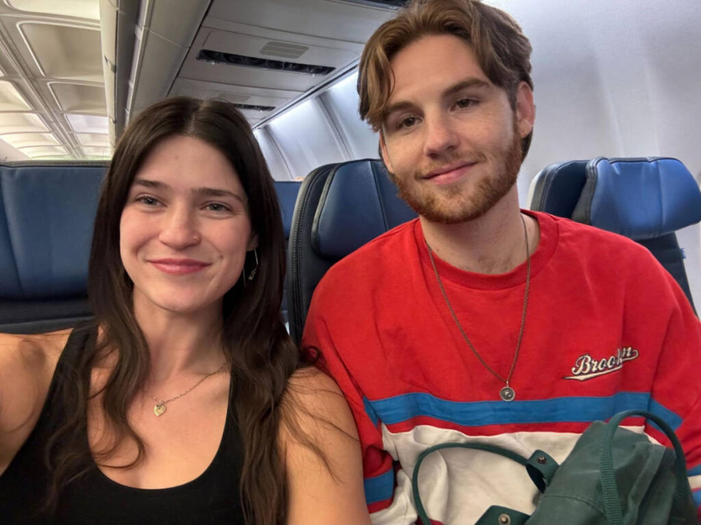 The author, Betty Hurd with her partner smiling for a selfie inside a plane