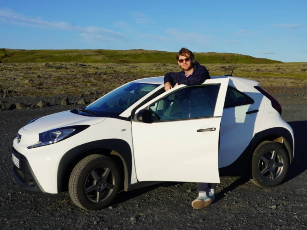 A man leaning on rented car in Iceland