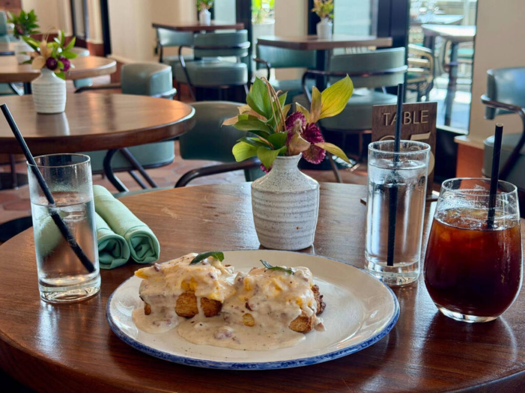 A plate with biscuits and gravy with drinks on the side