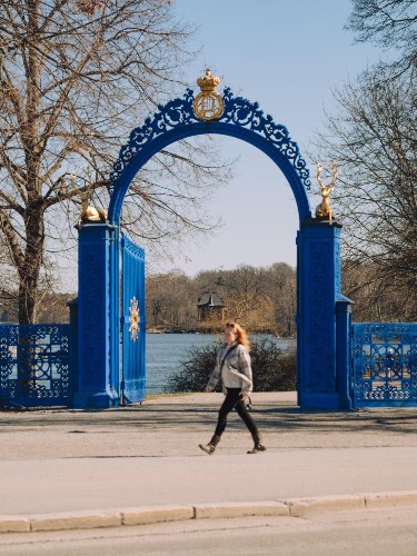 A woman walking in front of the blue gates of Bla Porten