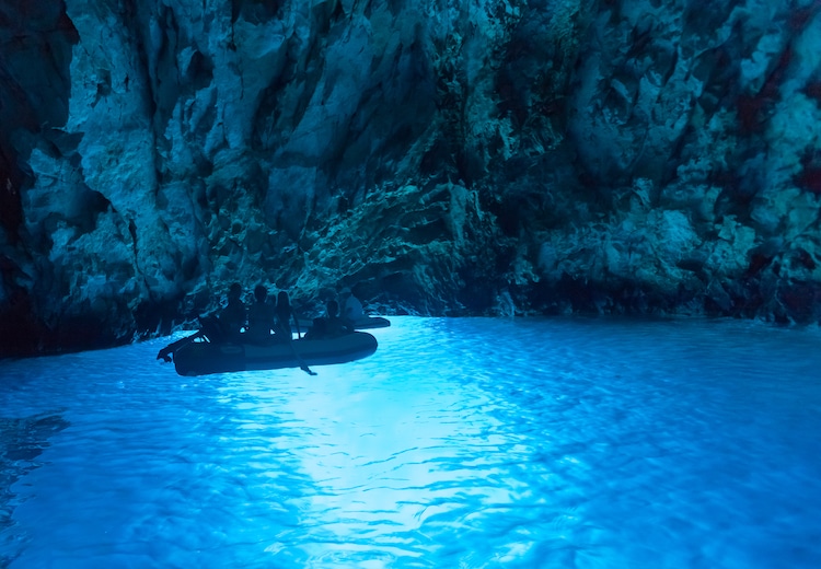 Tourists in inflatable boats inside the Blue cave