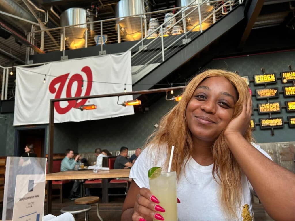 Travel Lemming writer, Alexandria Taylor smiling for a photo while holding a cocktail in Bluejacket Brewery