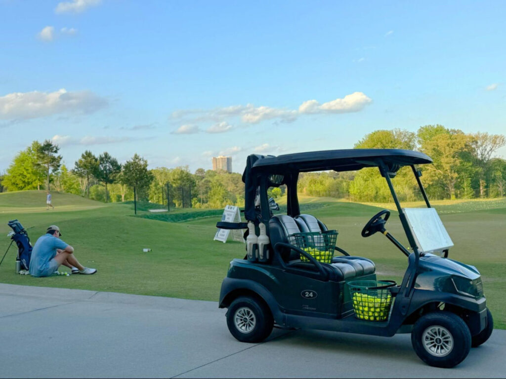 View of a parked golfcart and a golfer resting at Bobby Jones Golf Course