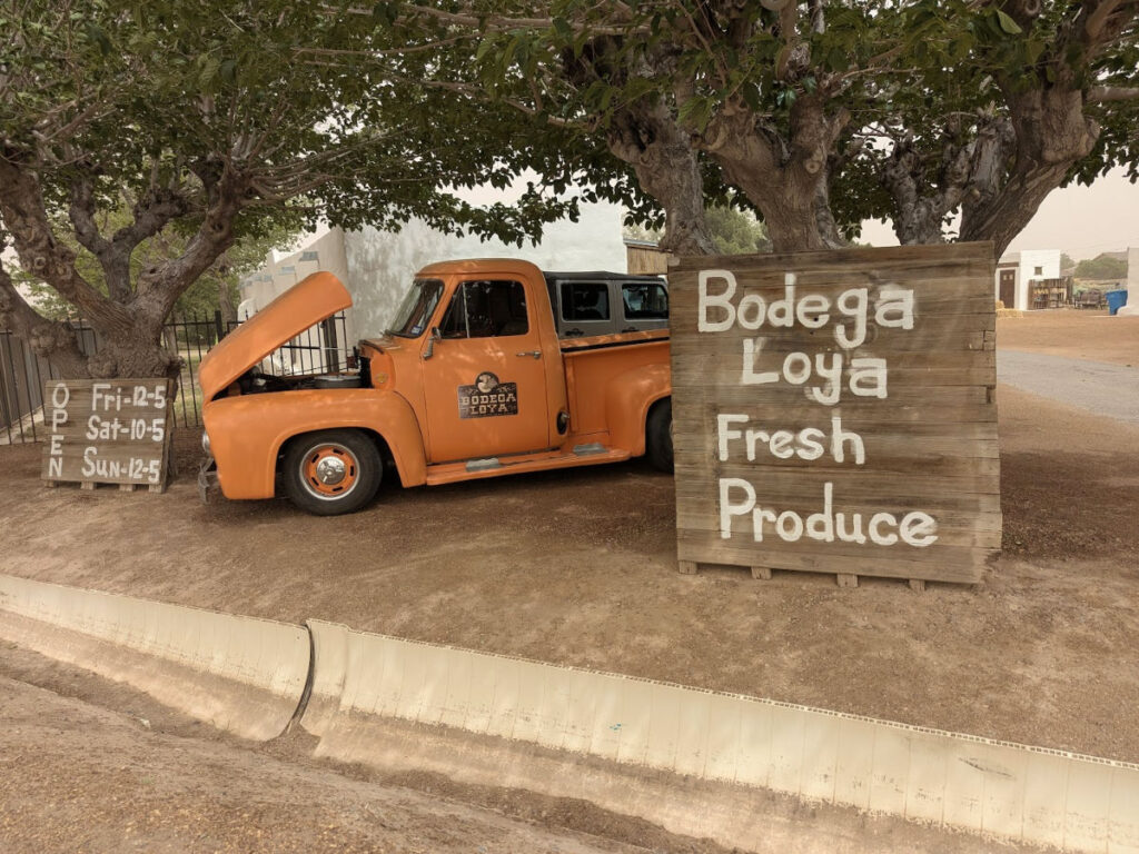 The Bodega Loya sign next to the old orange pickup truck