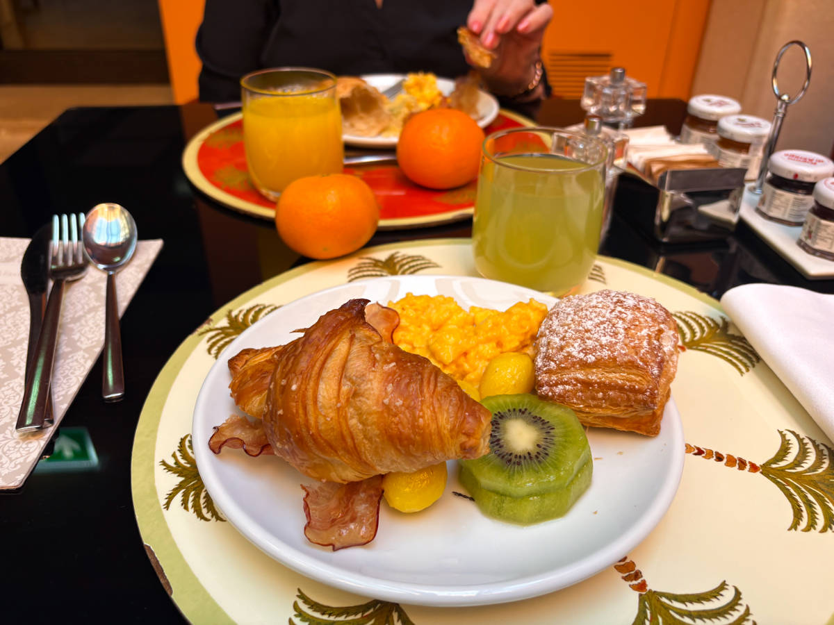 Closeup look of the plates with pastries, eggs and fruits with glasses of drinks on the side