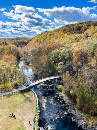 Aerial view of the bridge over the river surrounded by fall foliage in Croton Gorge Park 