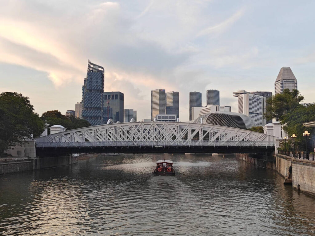A bumboat sailing along the Singapore River under the Cavenagh Bridge