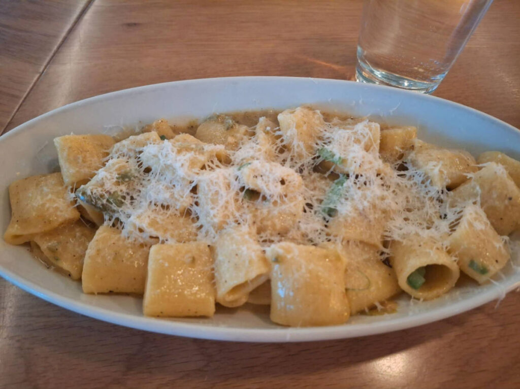 A plate of cacio e pepe rigatoni topped with more cheese